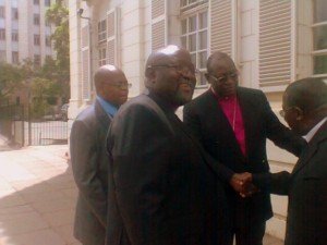 Bishop Chad Gandiya (centre) smiling after he won the ownership of Anglican Church property case in Harare today. Today's Supreme Court decision ended the six-year dispute between led by him Anglicans and Nolbert Kunonga's Church of the Province of Zimbabwe. In the background: Dr Julius Makoni of Manicaland and Registrar of the Anglican Church, Michael Chigore, who served as lawyer representing Bishop Gandiya in the court. (Photo M. Chibaya)