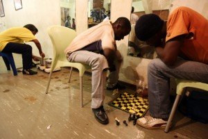 South Africa / Urban refugees / Boys play chess, while a woman cooks. The Central Methodist Church in central Johannesburg provides shelter to in excess of 3,800 Zimbabwean refugees. People sleep wherever they can find a surface to lie. / UNHCR / JAMES OATWAY / 6 August 2009